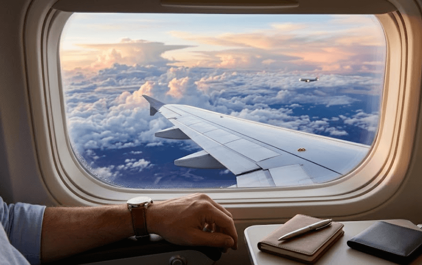 A view of clouds and an aircraft wing through an airplane window.